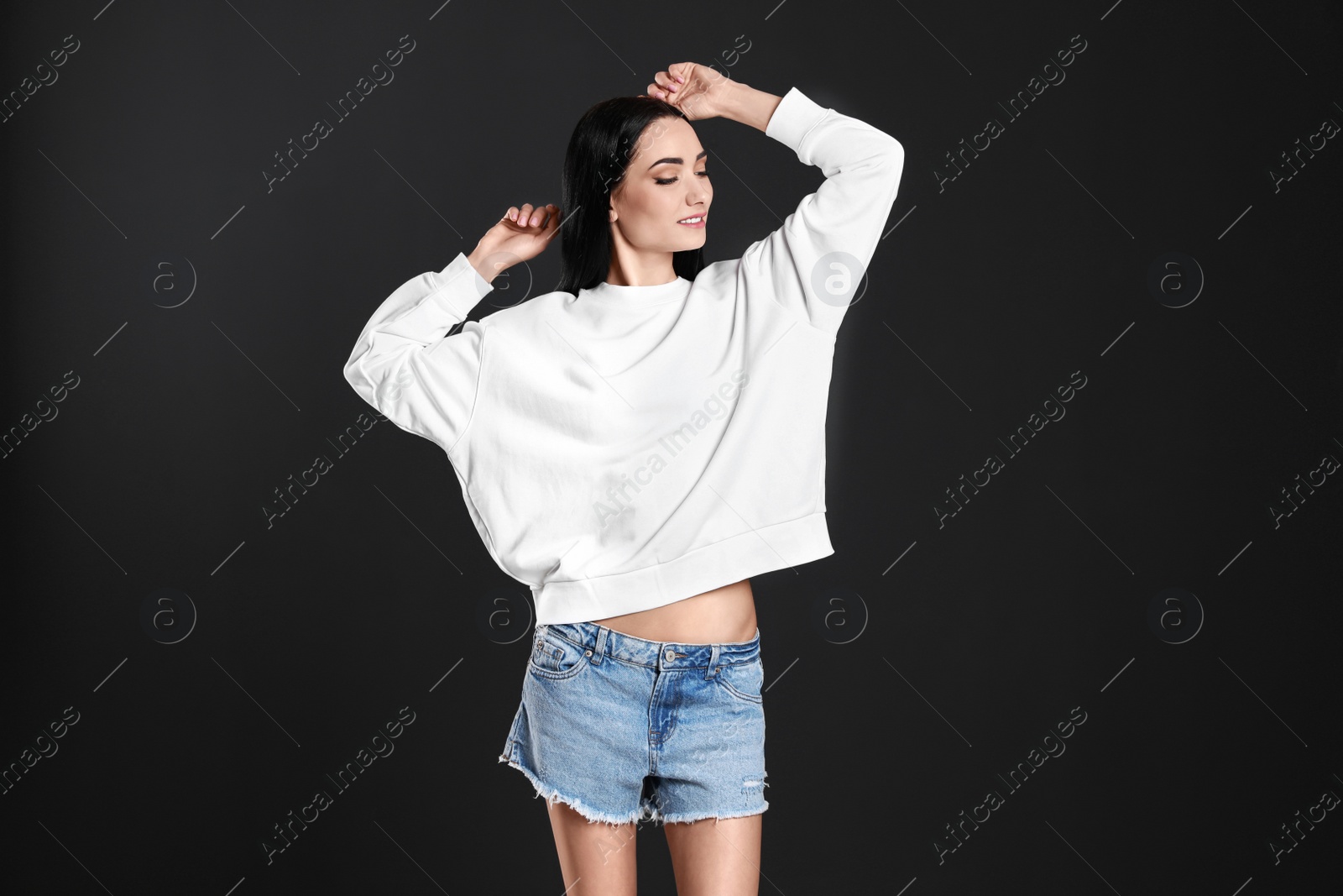 Photo of Portrait of young woman in sweater on black background. Mock up for design