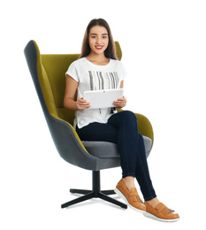 Young woman with tablet sitting in armchair on white background