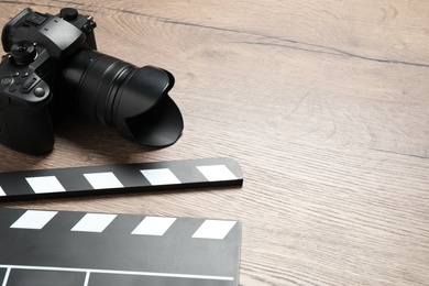 Photo of Clapboard with camera and space for text on wooden background. Video production industry