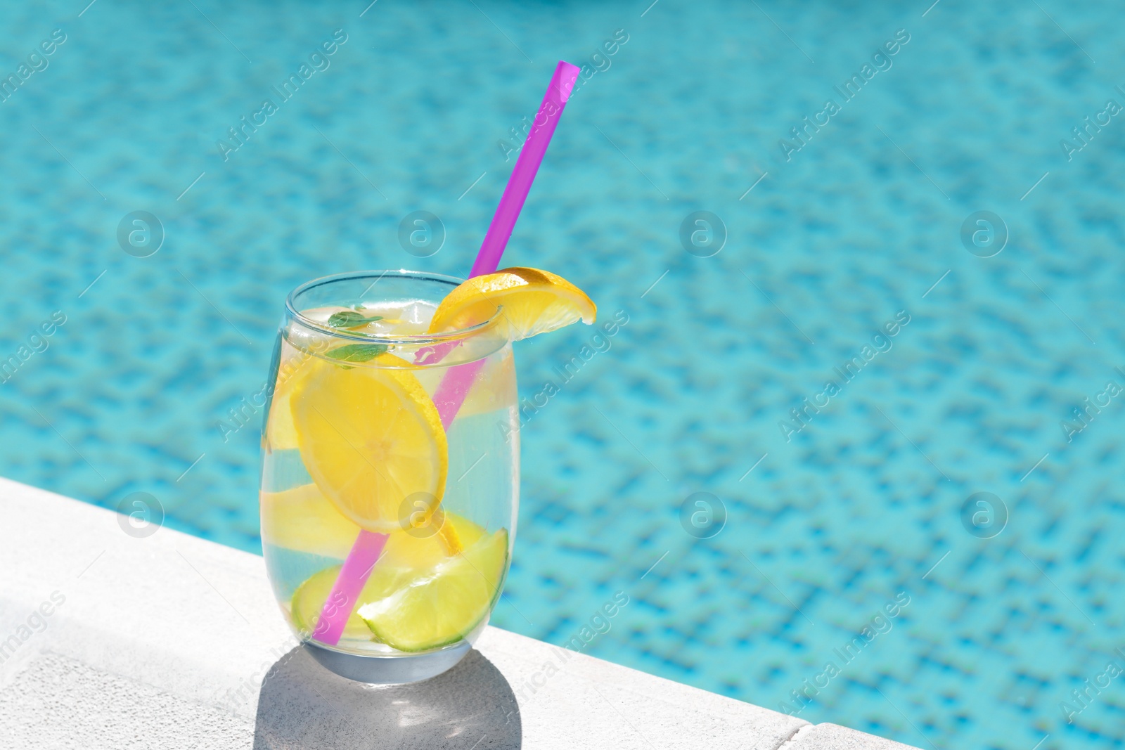 Photo of Refreshing water with lemon slices and mint near swimming pool. Space for text