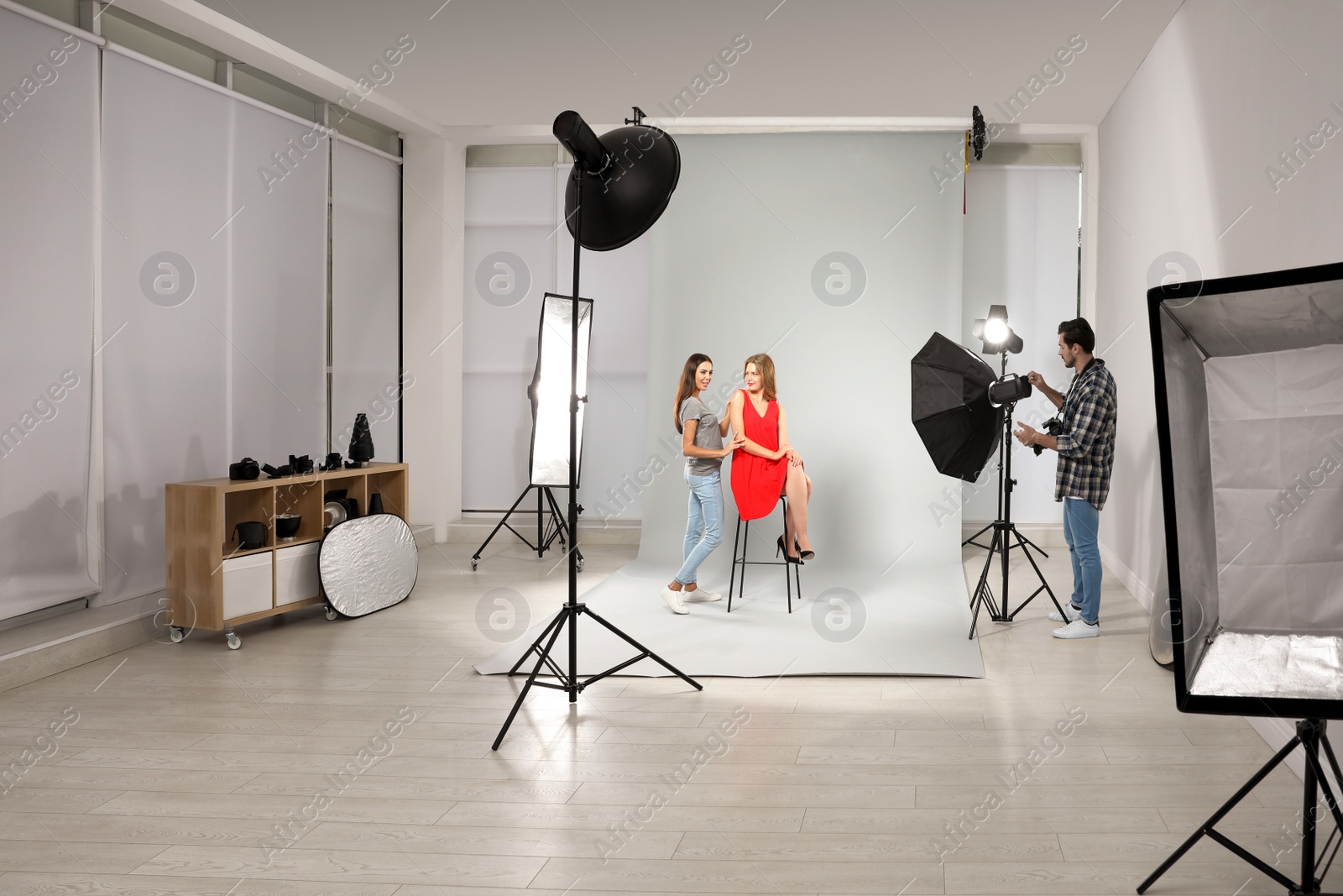 Photo of Professional photographer and assistant working with model in modern studio