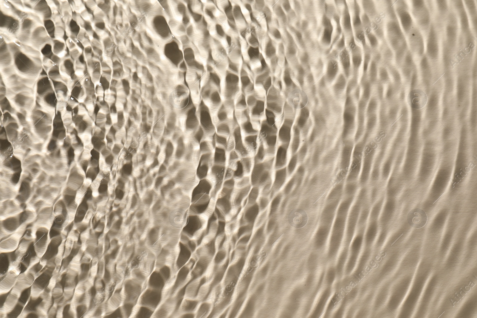 Photo of Rippled surface of clear water on beige background, top view