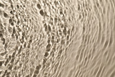 Rippled surface of clear water on beige background, top view