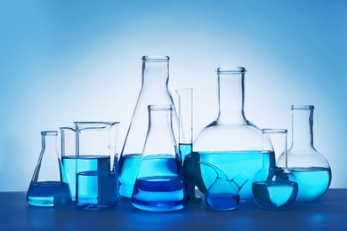 Photo of Laboratory glassware for chemical analysis with blue liquid on table against white background