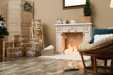 Fireplace with burning candles in festive room interior. Christmas celebration