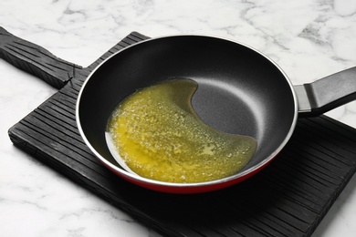 Photo of Frying pan with melting butter on marble table
