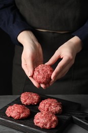 Photo of Woman making meatball from ground meat at grey table, closeup