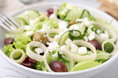 Photo of Bowl of tasty salad with leek, olives and cheese on white table, closeup