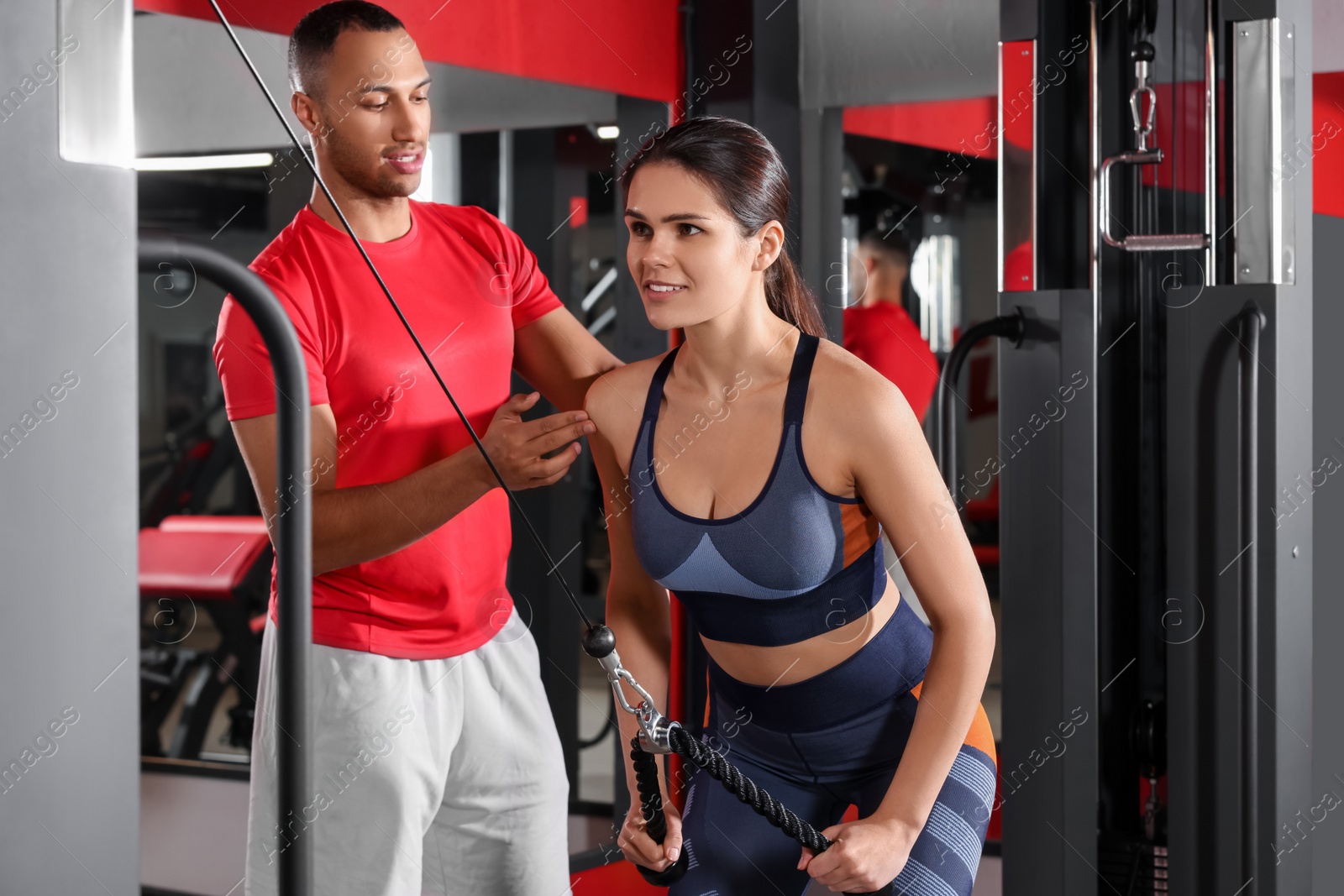 Photo of Trainer explaining woman how to do exercise properly in modern gym