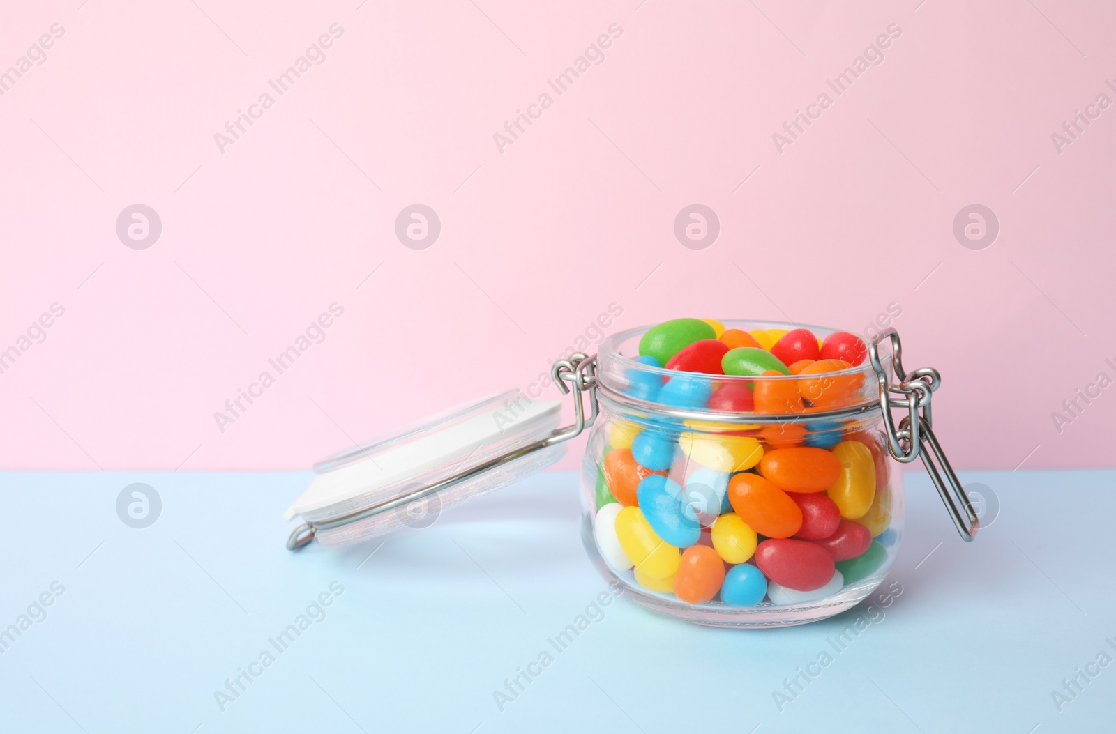 Photo of Jar of delicious jelly beans on color background. Space for text