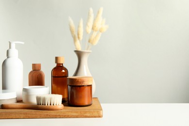 Different bath accessories and spikes on white table against grey background. Space for text