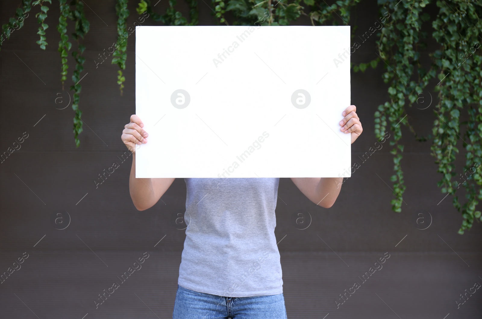 Photo of Woman holding blank poster outdoors. Mockup for design