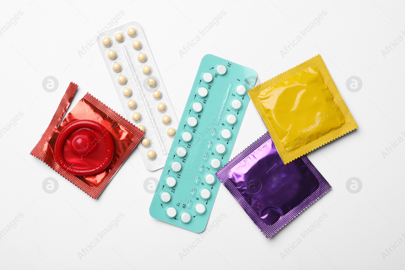 Photo of Condoms and birth control pills on white background, top view. Safe sex concept