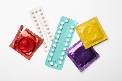 Condoms and birth control pills on white background, top view. Safe sex concept