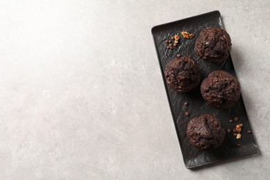 Photo of Delicious chocolate muffins on light table, top view. Space for text