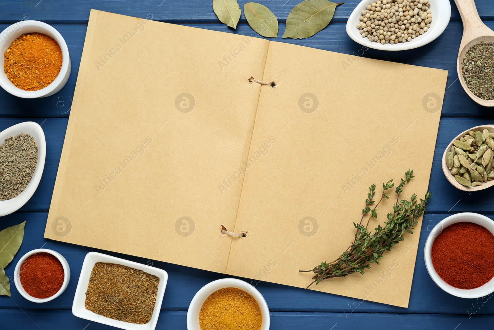 Photo of Blank recipe book surrounded by different ingredients on blue wooden table, flat lay. Space for text