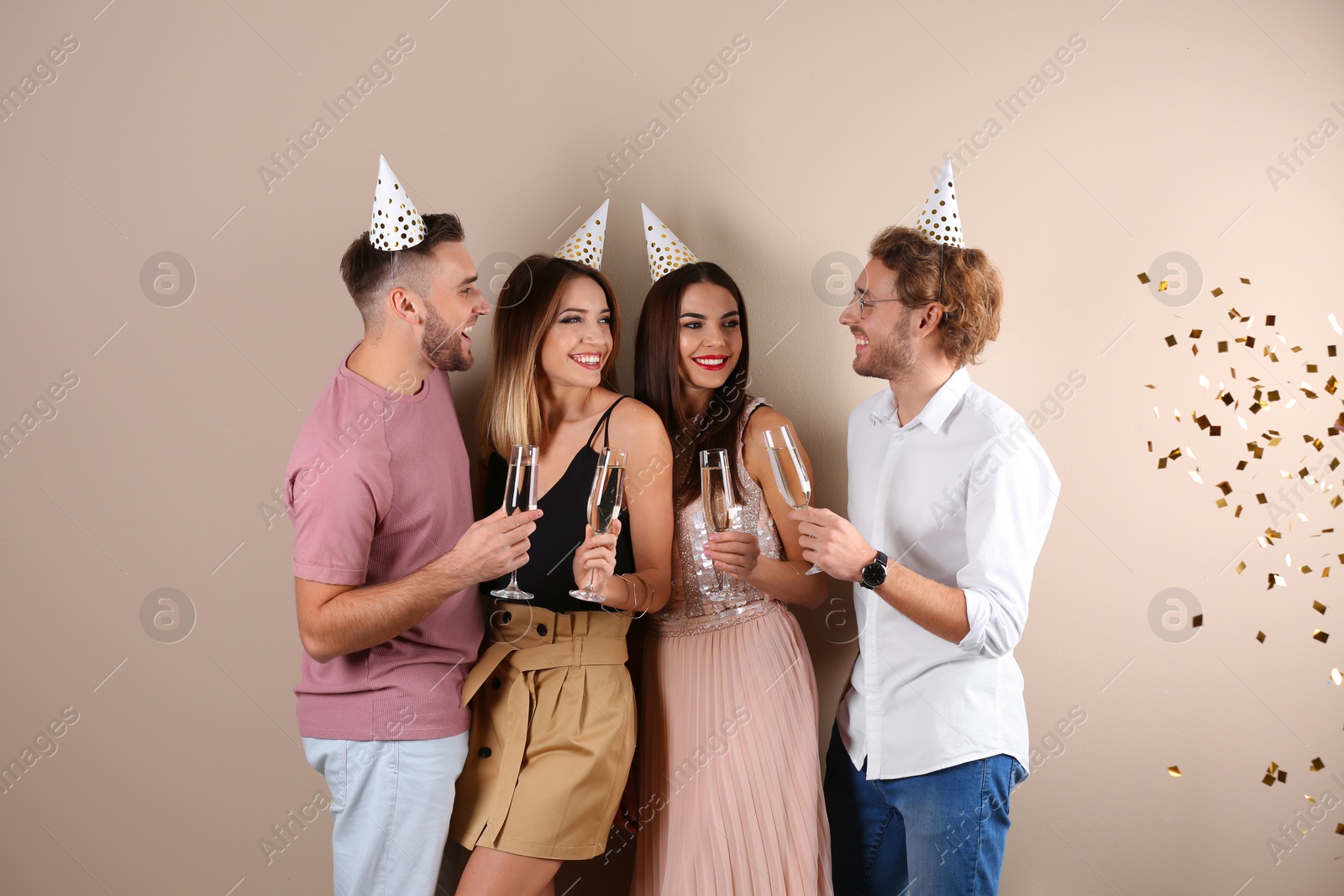 Photo of Happy friends with champagne in glasses on color background