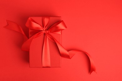 Photo of Beautiful gift box with bow on red background, top view. Space for text