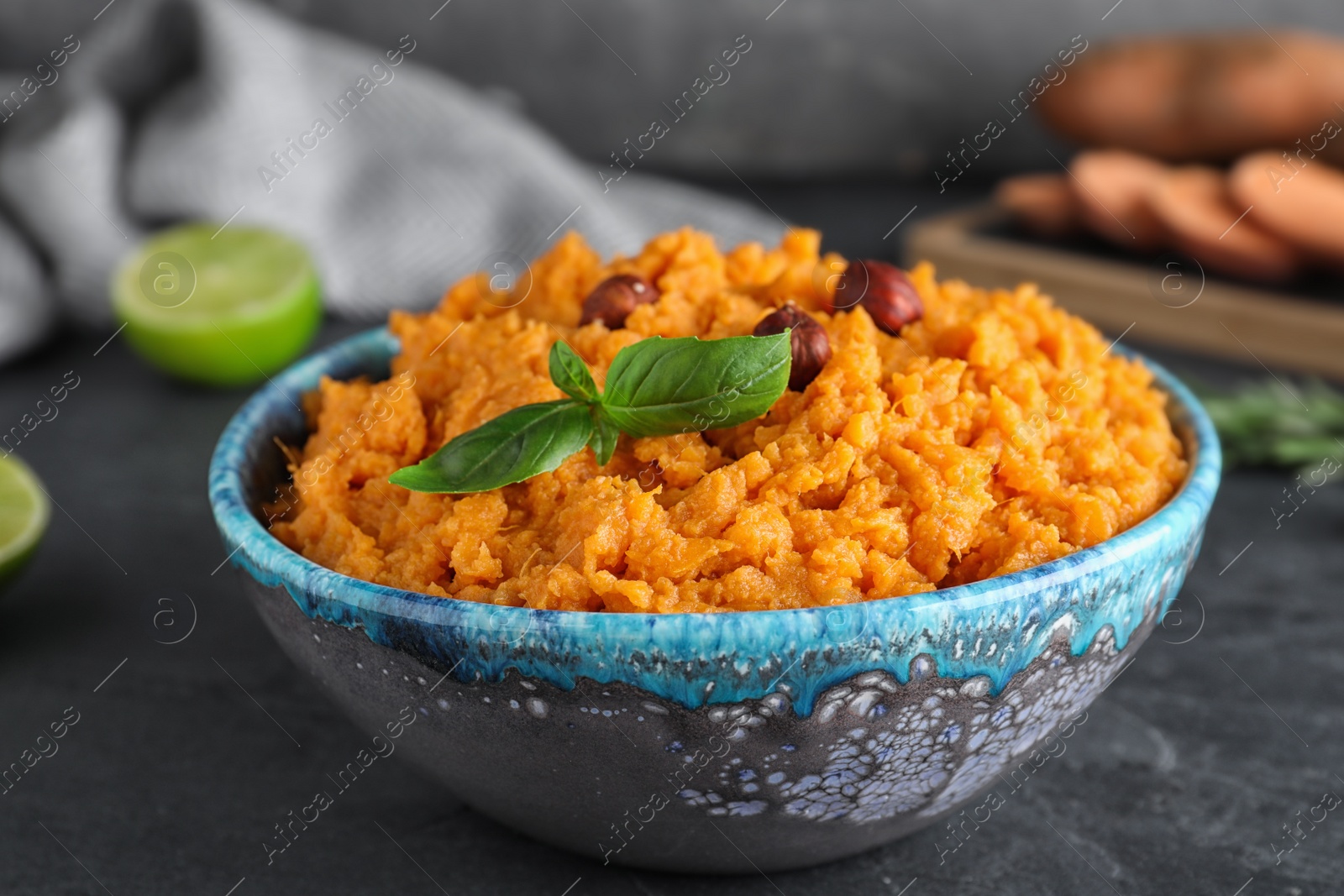 Photo of Bowl with mashed sweet potatoes on grey table