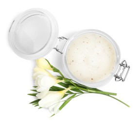 Photo of Jar of exfoliating salt scrub and freesia flowers on white background, top view