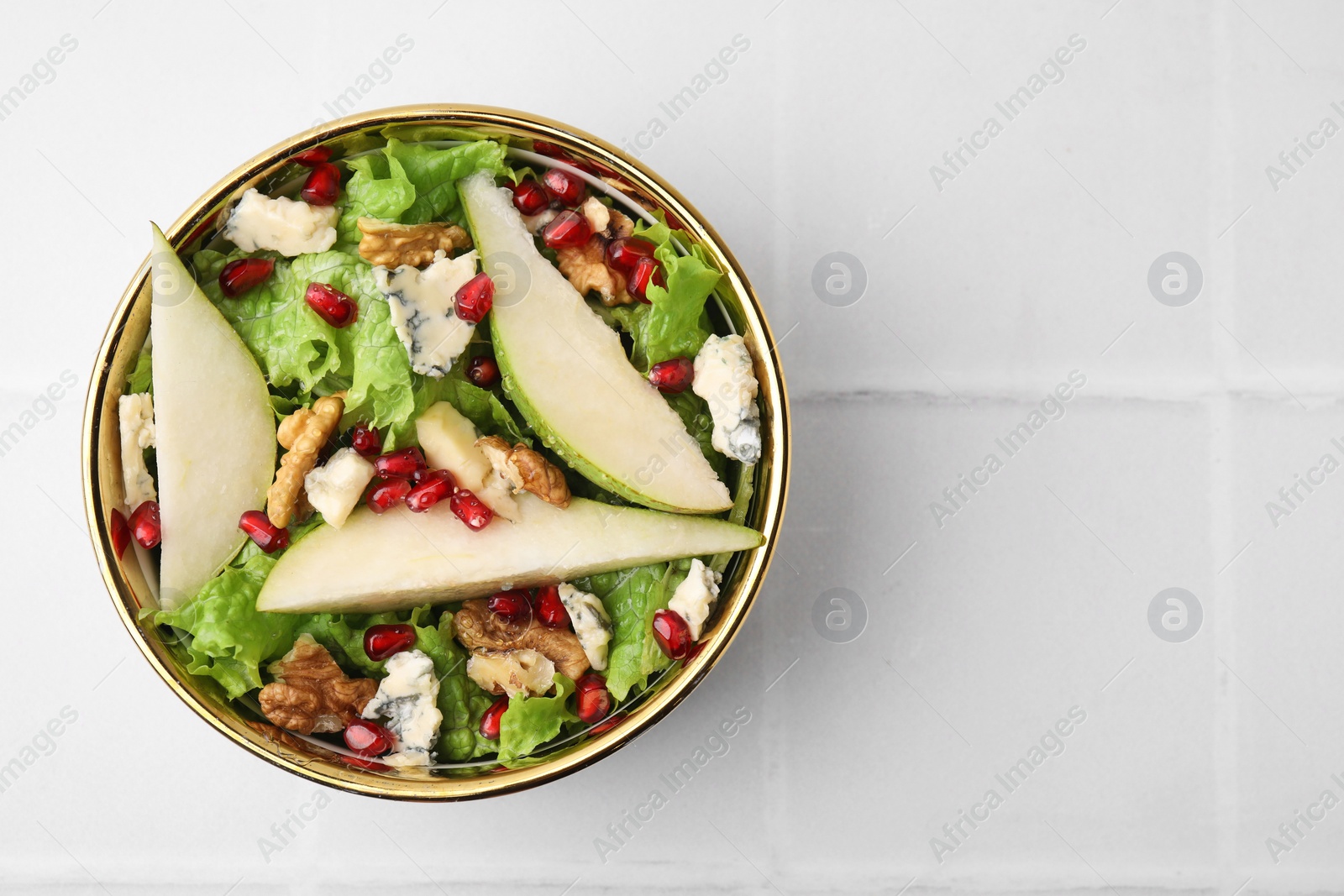 Photo of Delicious pear salad in bowl on light tiled table, top view. Space for text