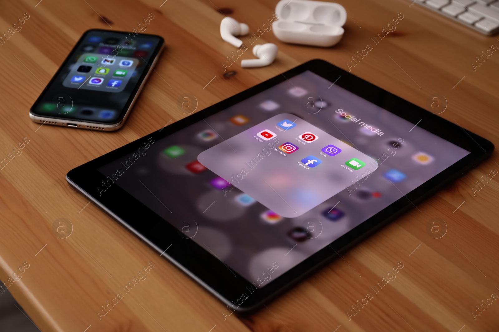 Photo of MYKOLAIV, UKRAINE - AUGUST 11, 2021: Tablet, smartphone and earphones on wooden table. Screens with social media icons