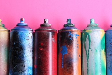 Photo of Many spray paint cans on pink background, flat lay