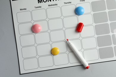 Photo of Timetable. Planner with bright magnets and red felt pen on grey table, top view