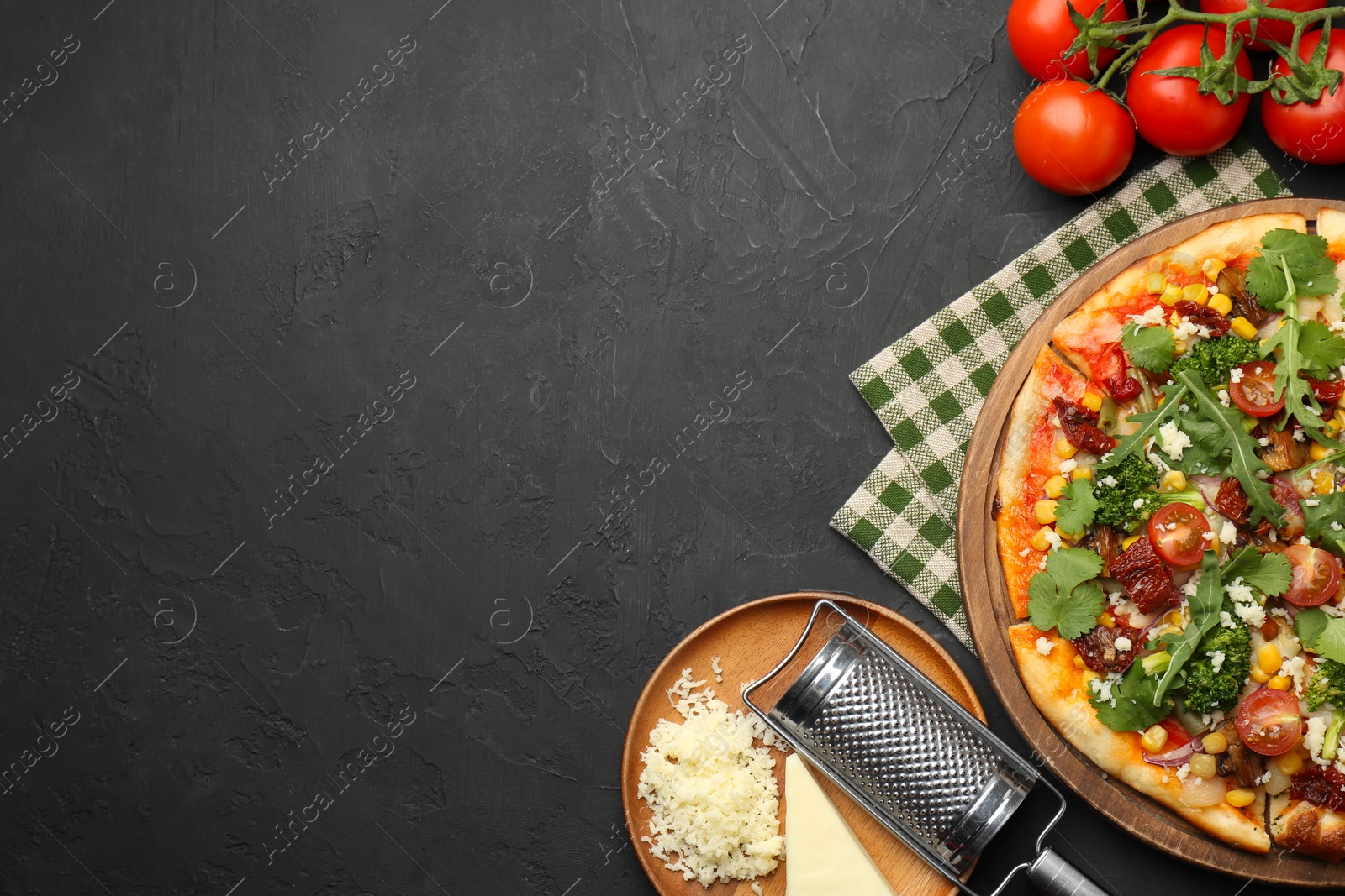 Photo of Delicious vegetarian pizza, ingredients and grater on black table, top view. Space for text