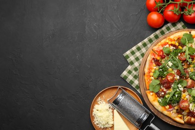 Photo of Delicious vegetarian pizza, ingredients and grater on black table, top view. Space for text