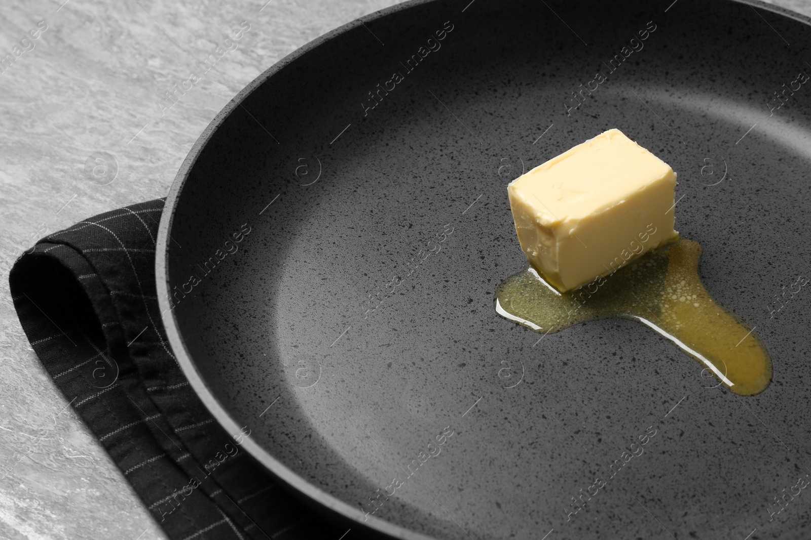 Photo of Frying pan with melting butter on grey table, closeup