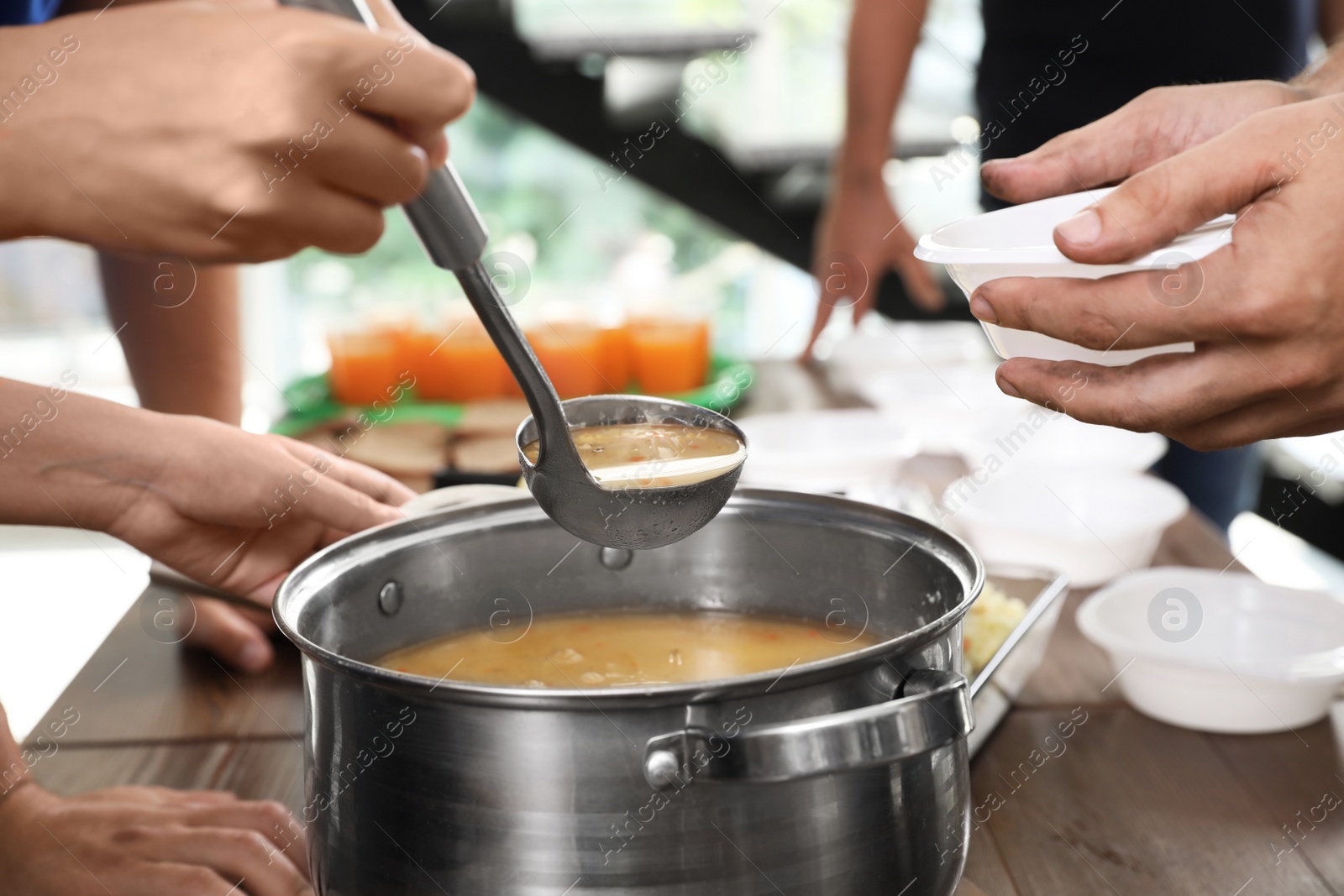 Photo of Volunteers serving food to poor people in charity centre, closeup