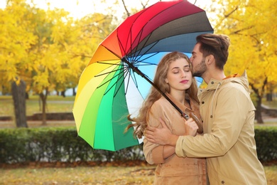 Happy couple with colorful umbrella in park