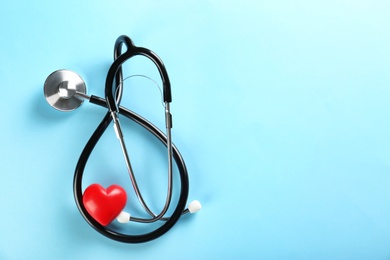 Photo of Stethoscope and small red heart on color background. Heart attack concept