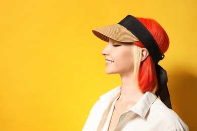 Beautiful young woman with bright dyed hair on orange background, space for text