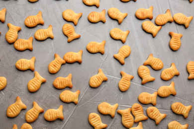 Delicious fish shaped crackers on grey table, flat lay