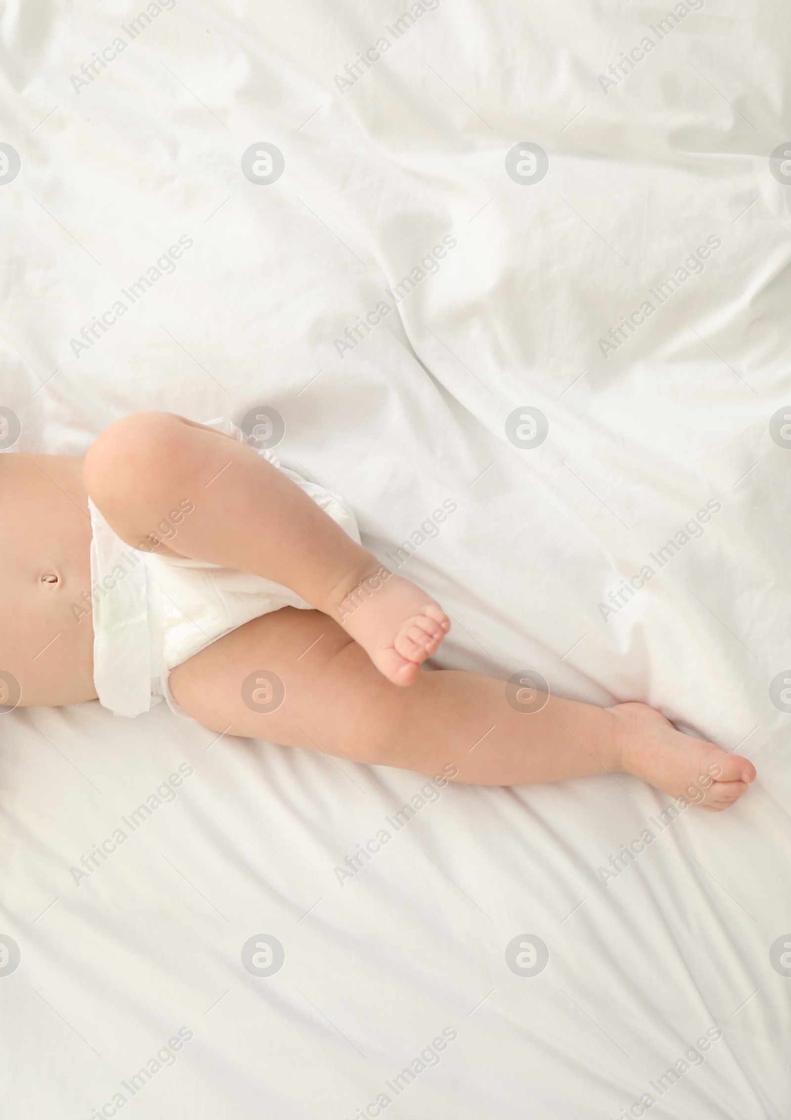 Photo of Cute little baby in diaper on bed, top view