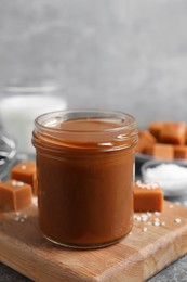 Photo of Yummy salted caramel in glass jar and candies on table