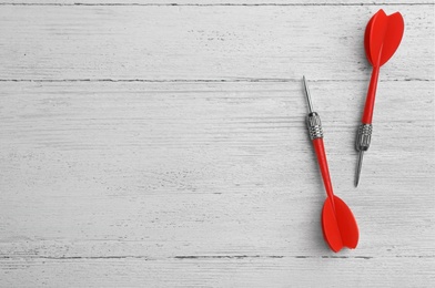 Photo of Red dart arrows on white wooden table, flat lay with space for text