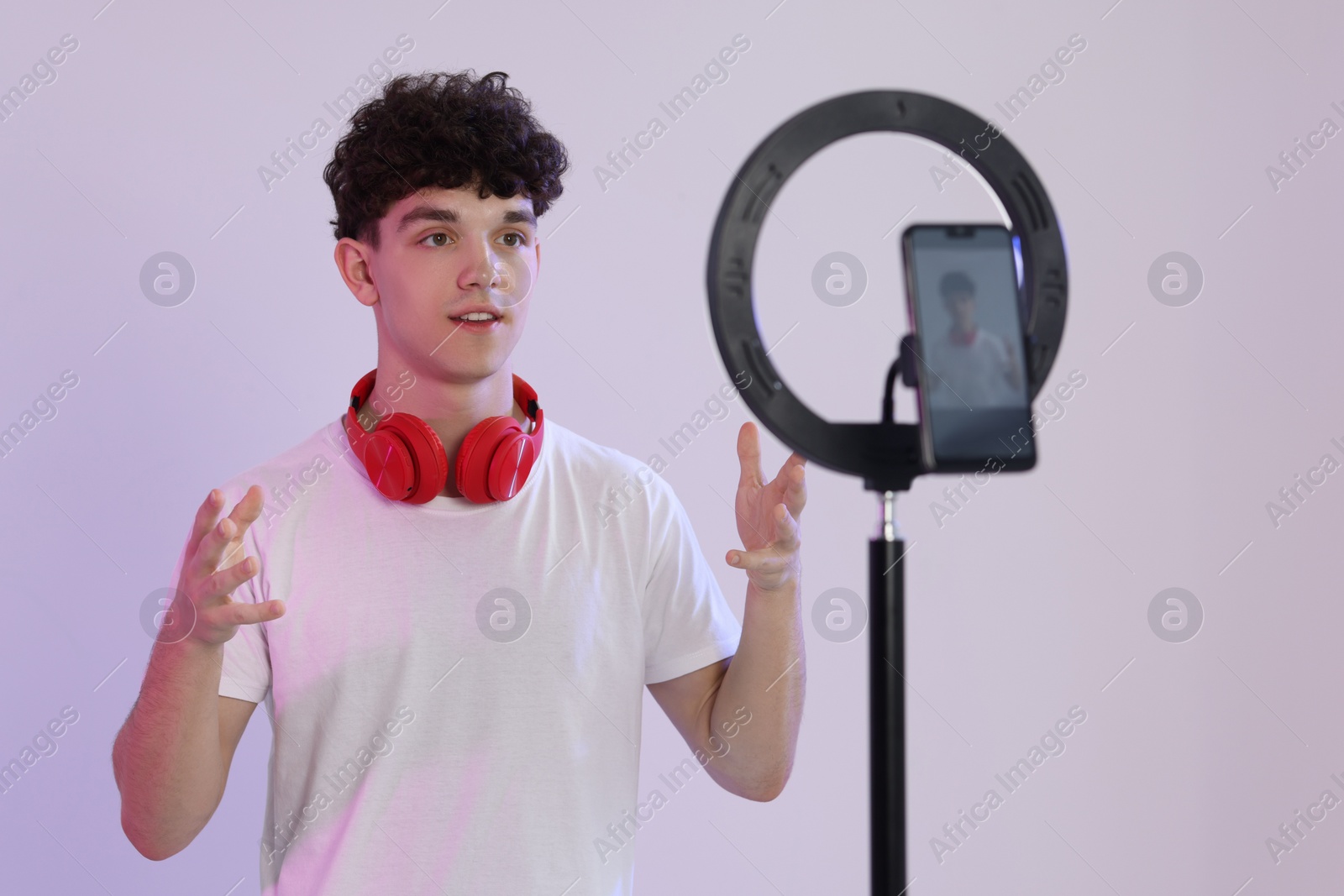 Photo of Teenage blogger explaining something while streaming on white background