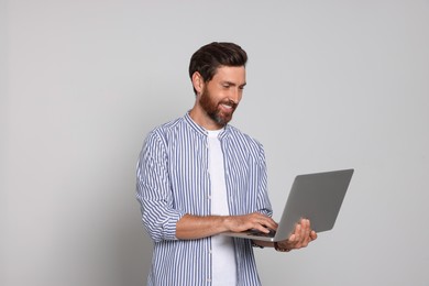 Photo of Handsome man holding laptop on light background