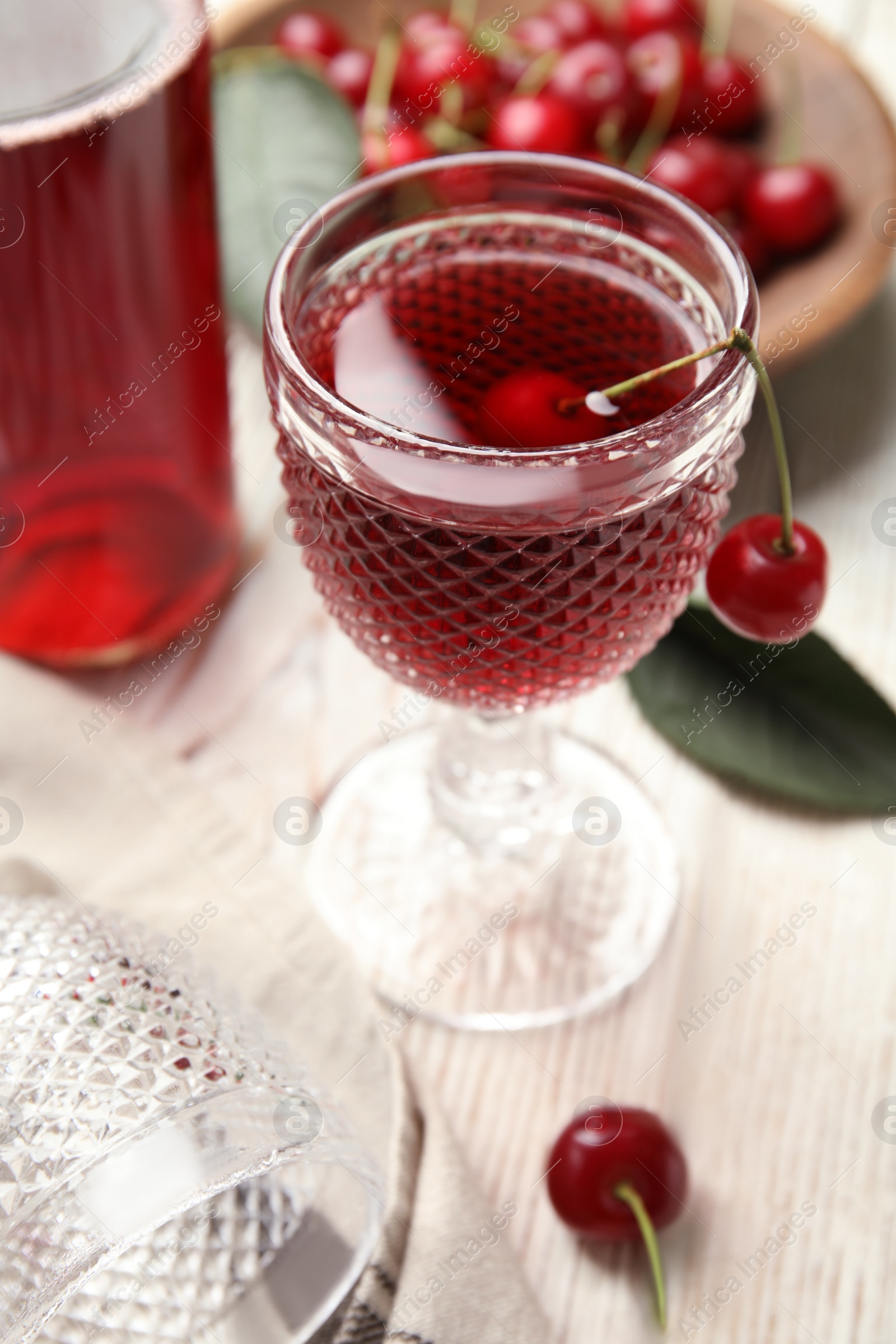 Photo of Delicious cherry wine with ripe juicy berries on white wooden table