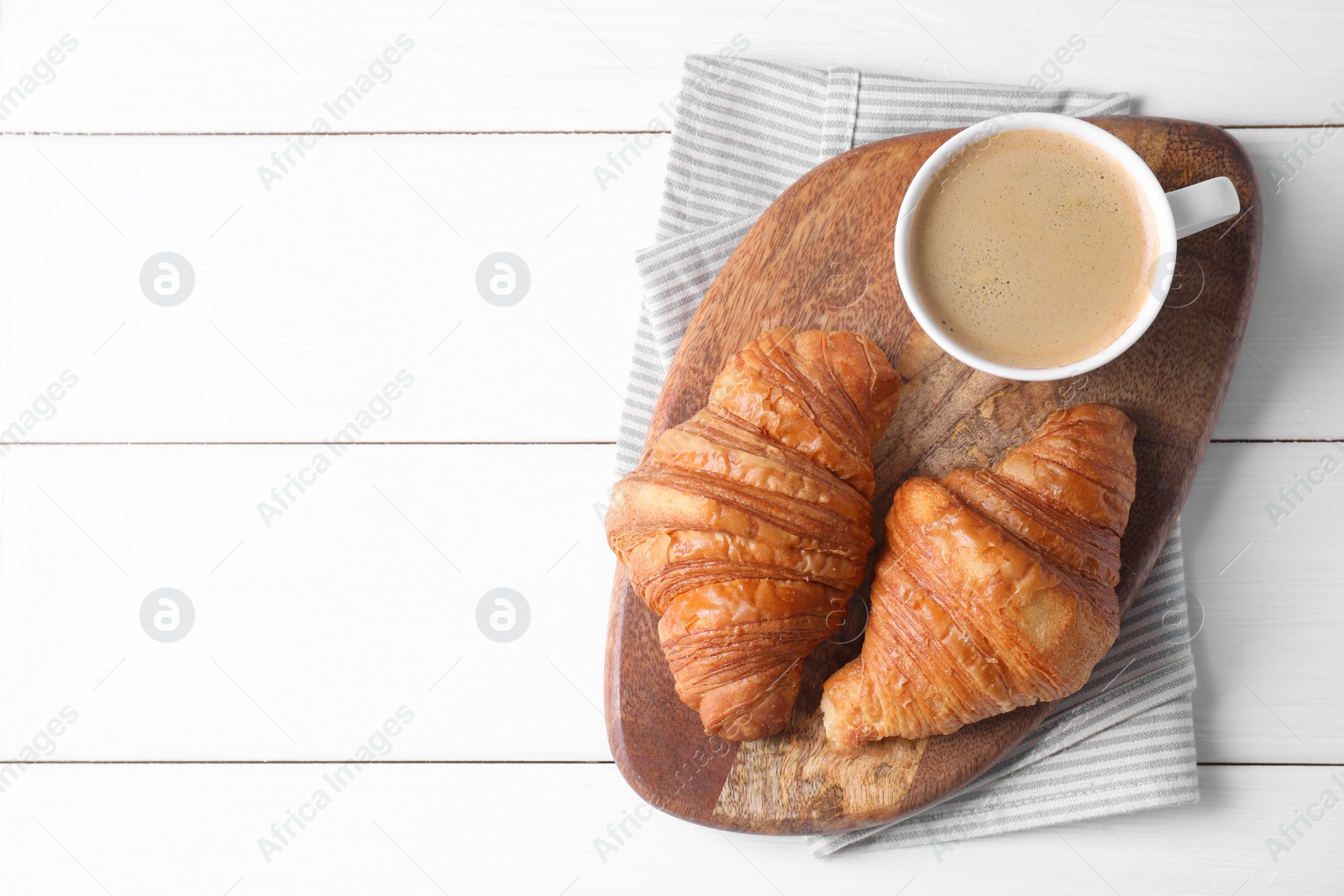 Photo of Tasty breakfast. Cup of coffee and croissants on white wooden table, top view. Space for text