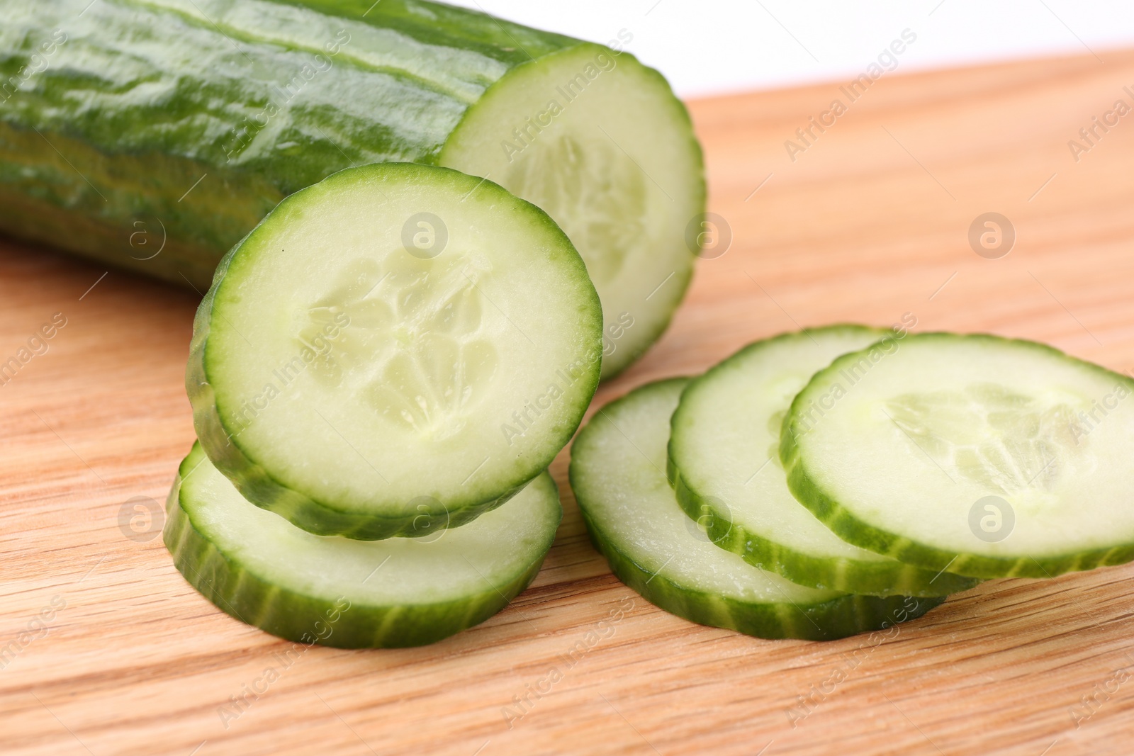 Photo of Cut ripe cucumber on wooden board, closeup