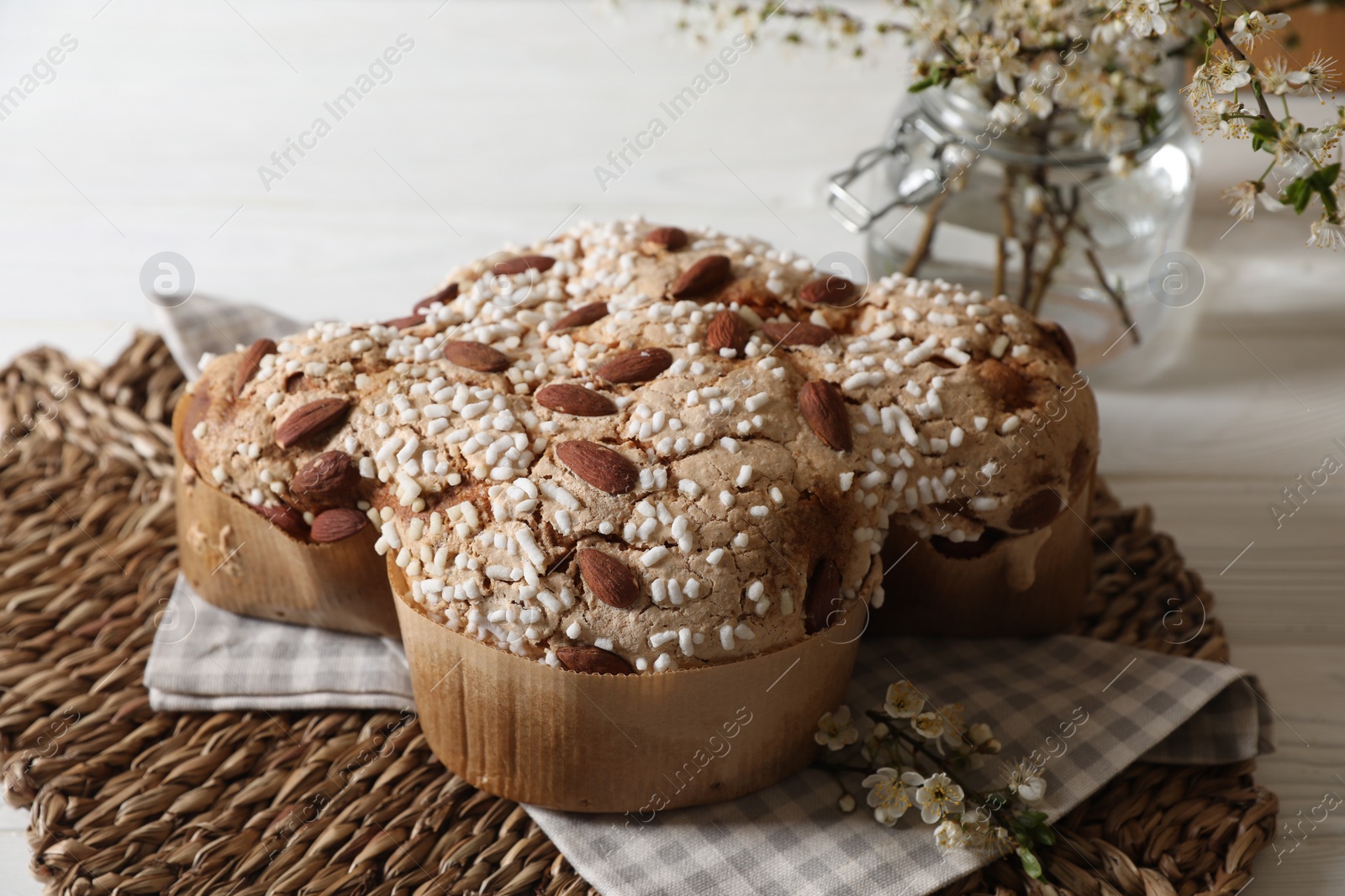 Photo of Delicious Italian Easter dove cake (Colomba di Pasqua) and flowers on white table