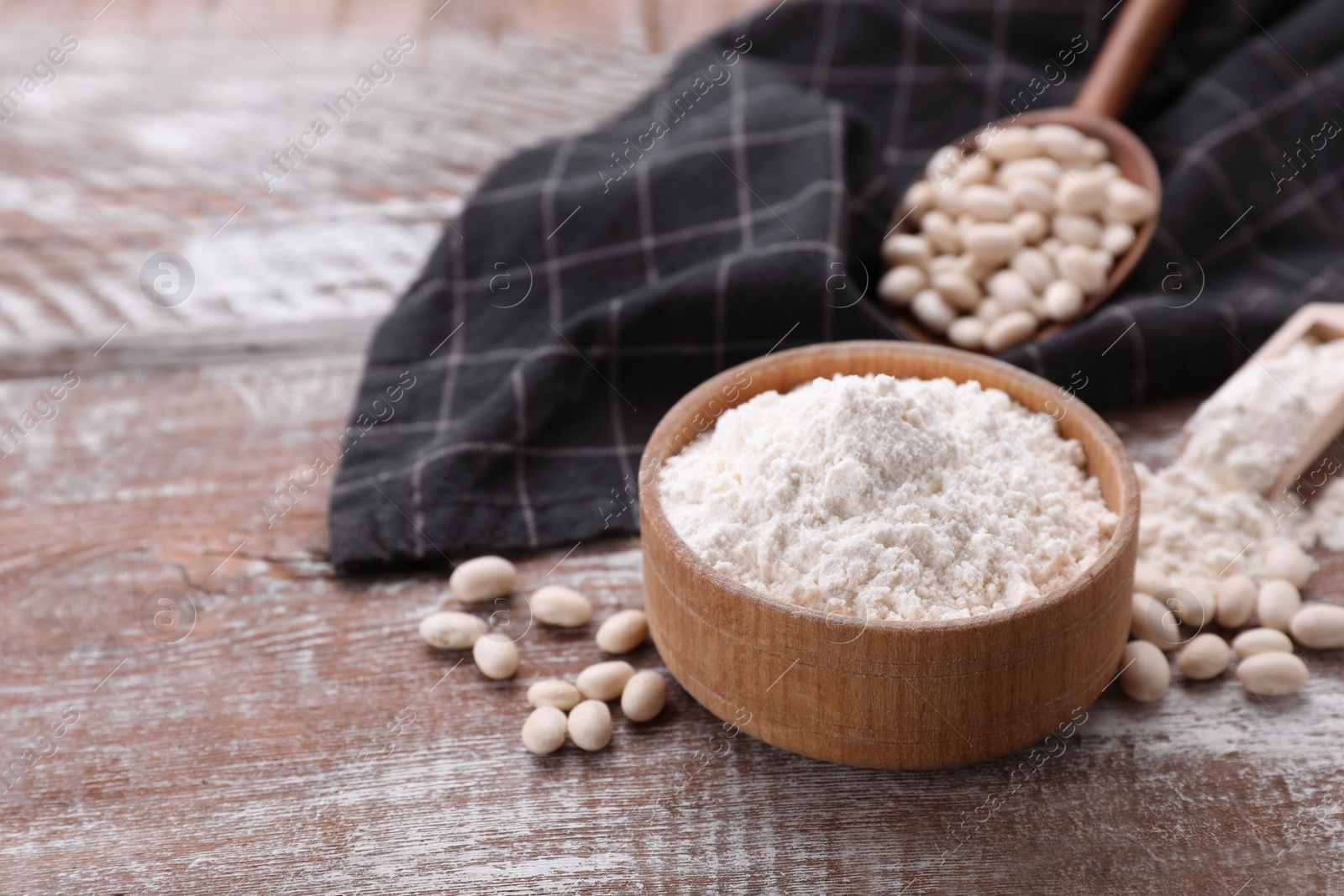 Photo of Bean flour and seeds on wooden table. Space for text