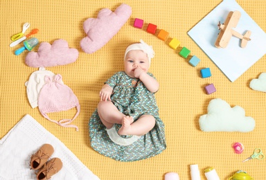 Photo of Cute little baby with clothing and accessories on color blanket, top view