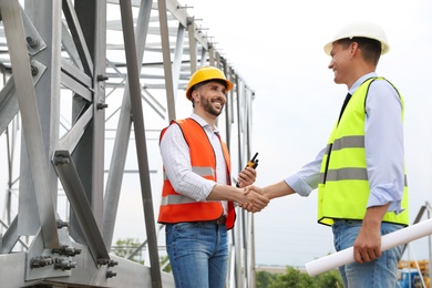 Professional engineers working on installation of electrical substation outdoors