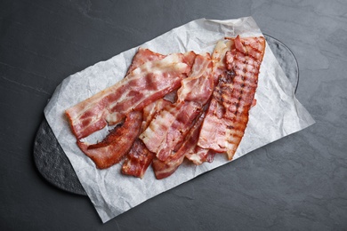 Slices of tasty fried bacon on dark table, top view