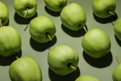 Many tasty fresh apples on green background